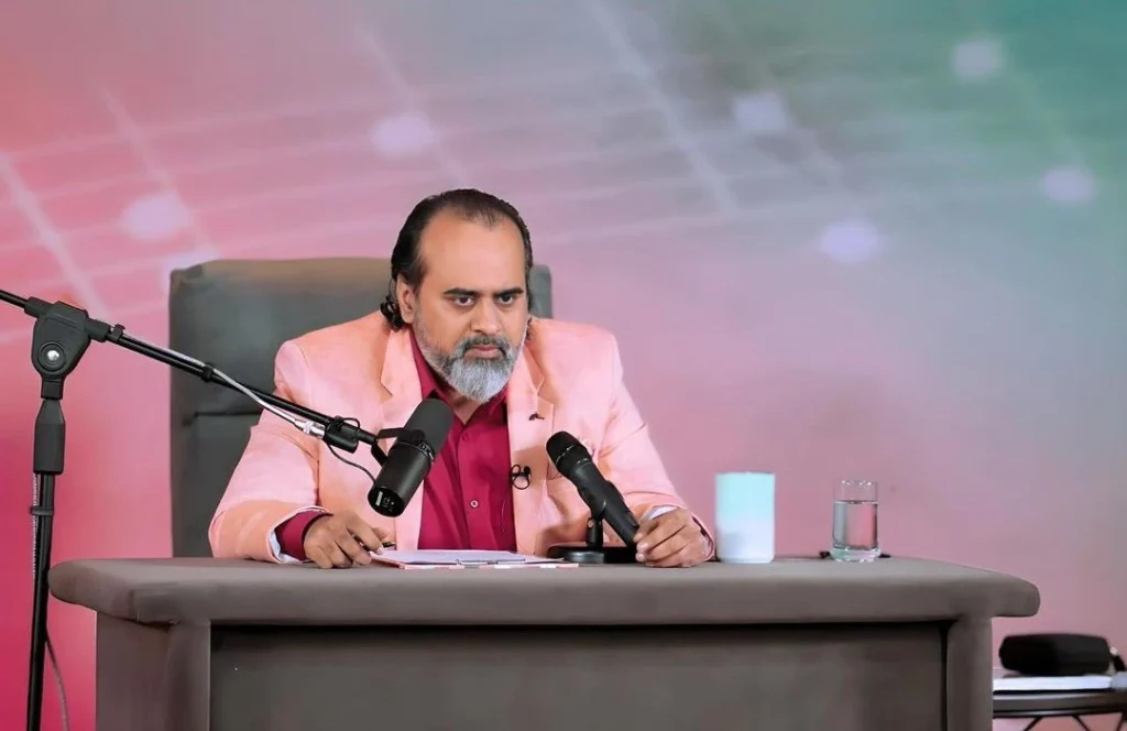 Acharya Prashant giving a seminar by sitting on a table with mic