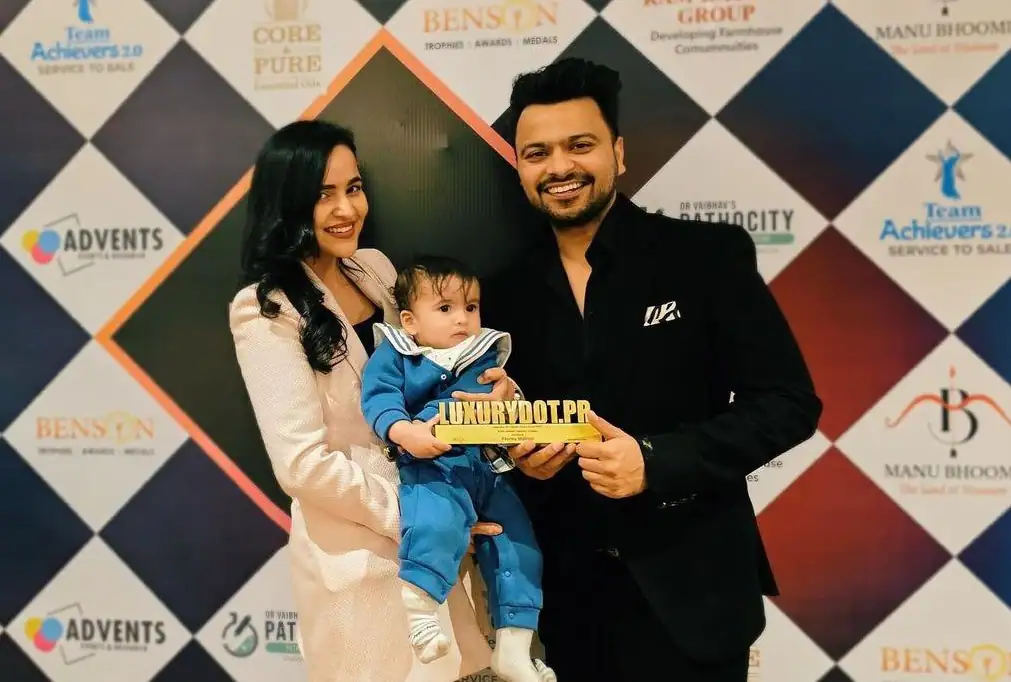 Prerna Malhan getting an award with her husband and son