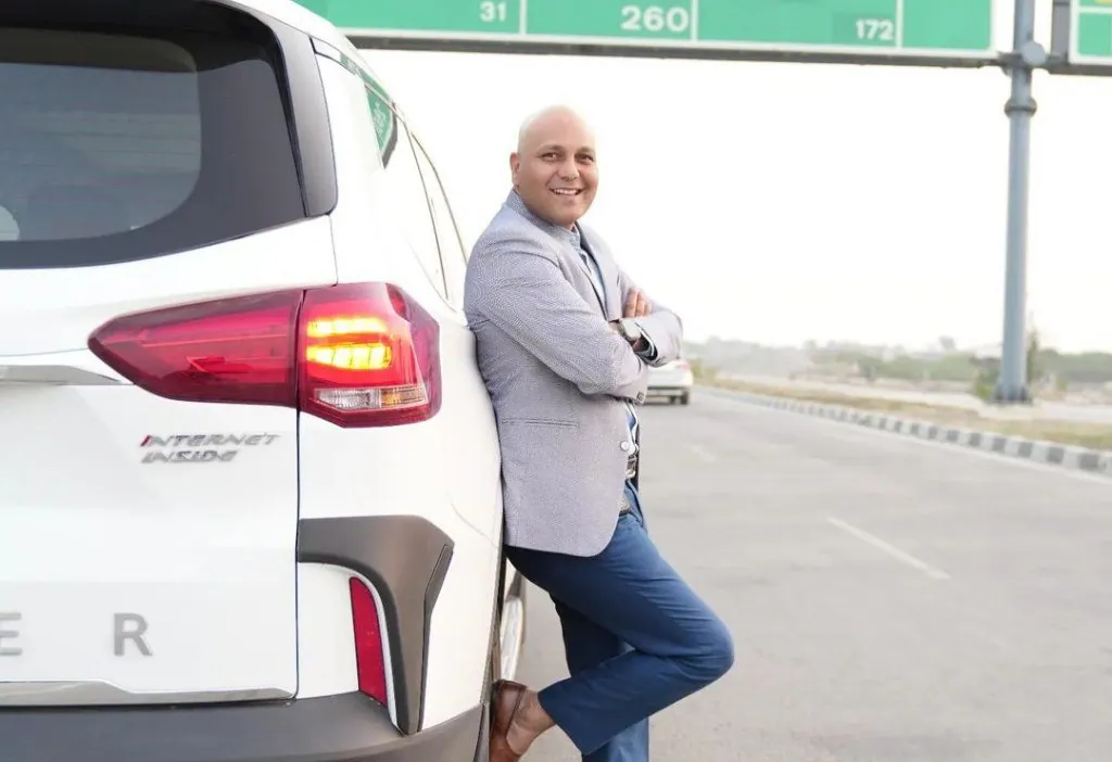 Harshvardhan Jain standing beside his car